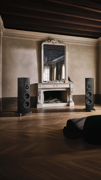 Pair of Sonus faber Amati G5 floorstanding speakers in Graphite wood finish, complementing a room with a cozy fireplace.