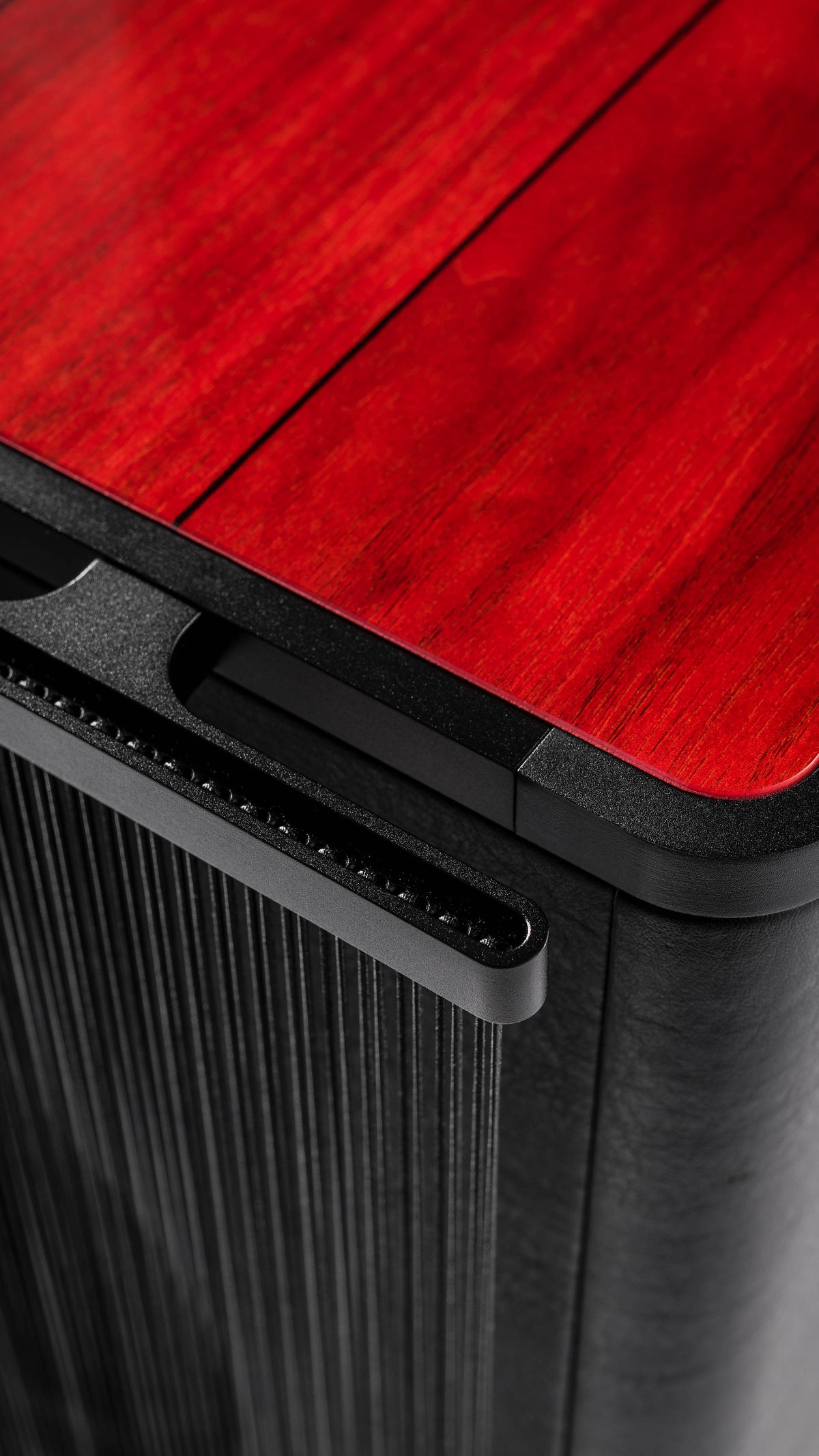 Close-up view of the Sonus faber Gravis VI subwoofer, highlighting the captivating red wood and black leather finish.
