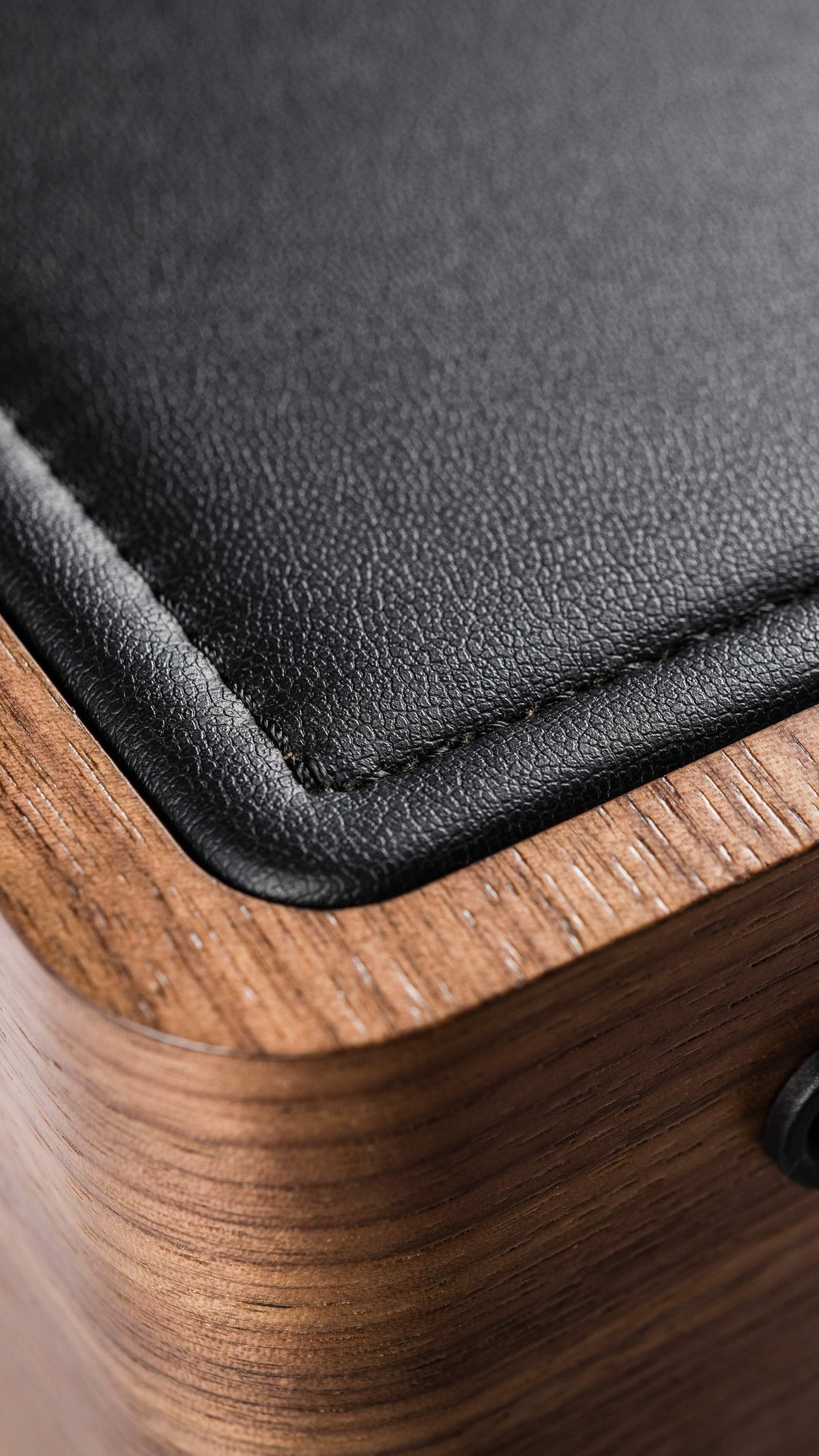 Close-up of the walnut wood and black leather top on a Sonus faber Gravis II subwoofer, showcasing natural materials.