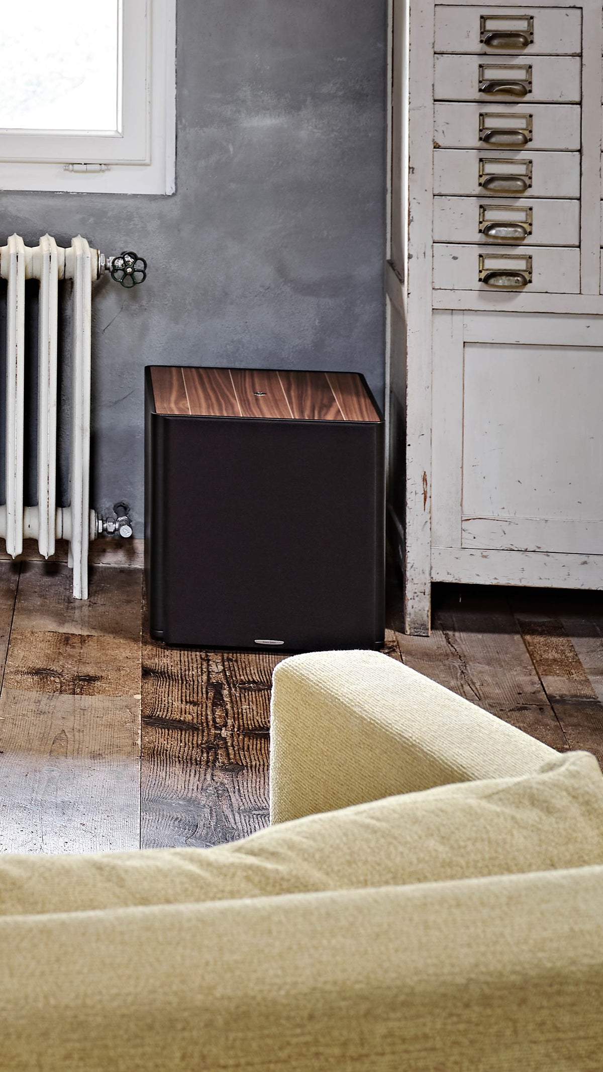 Sonus faber Gravis III subwoofer in walnut wood, complementing Olympica Nova speakers in a home audio setup with a TV.