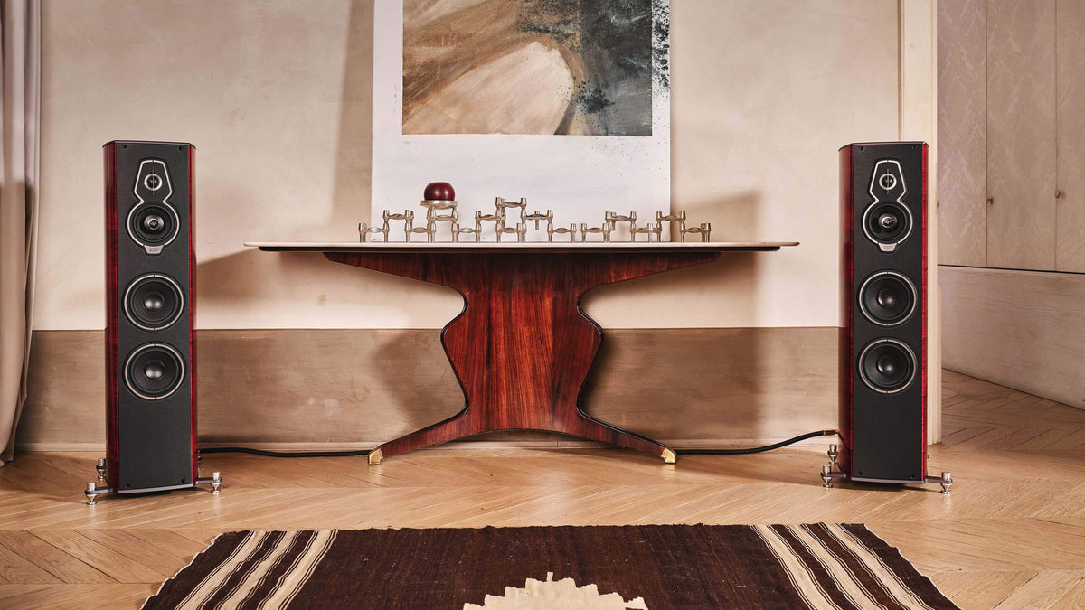 Pair of Sonus faber Serafino G2 speakers in Red Wood Italian leather finish, flanking an elegant table in a stylish home setting.