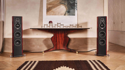 Pair of Sonus faber Serafino G2 speakers in Red Wood Italian leather finish, flanking an elegant table in a stylish home setting.