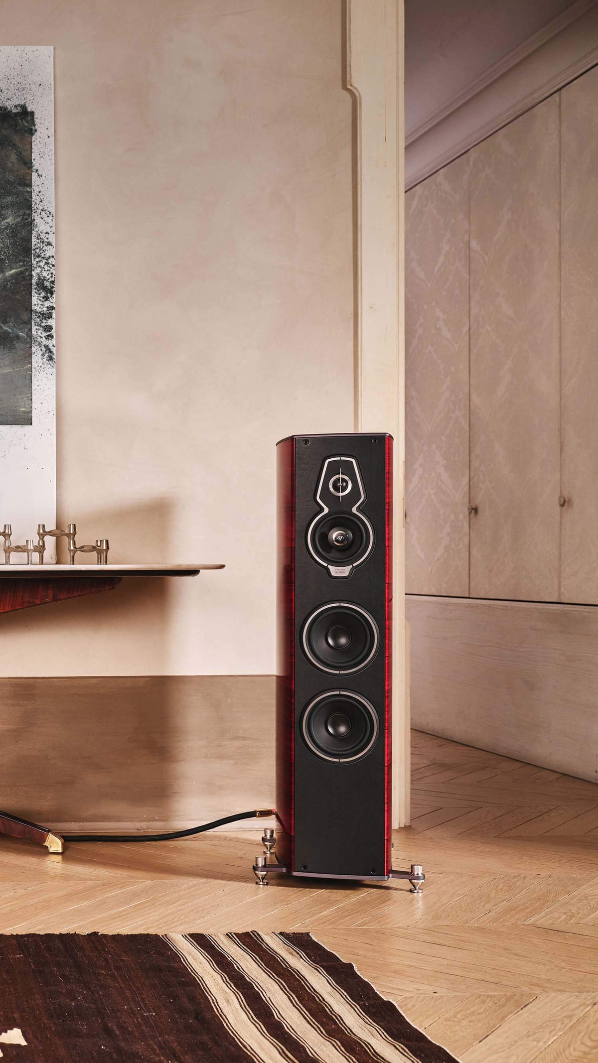 Pair of Sonus faber Serafino G2 speakers in Red Wood Italian leather finish, flanking an elegant table in a stylish home setting.