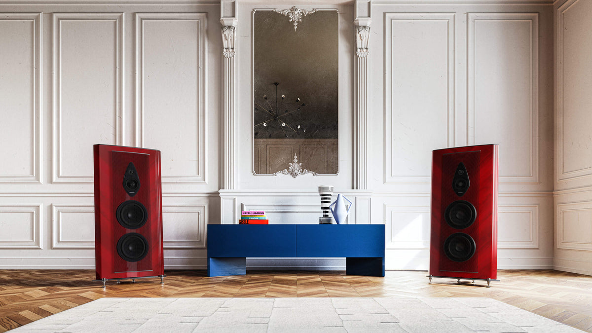 Red-finished Sonus faber Stradivari G2 speakers, framing a table with books in a luxurious room for an elegant audio setup.